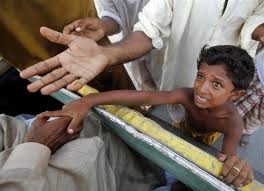 “Small Palestinian boy in a crowd reaching forward with empty hands for food”
