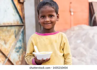 “Hungry child holding a food bowl, with a small hopeful smile on his face”